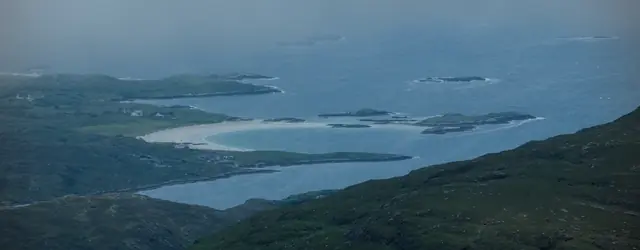 Moody lakes and hills under low cloud, seen from a ridgeline