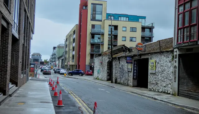 A quiet city street between old walls and new buildings